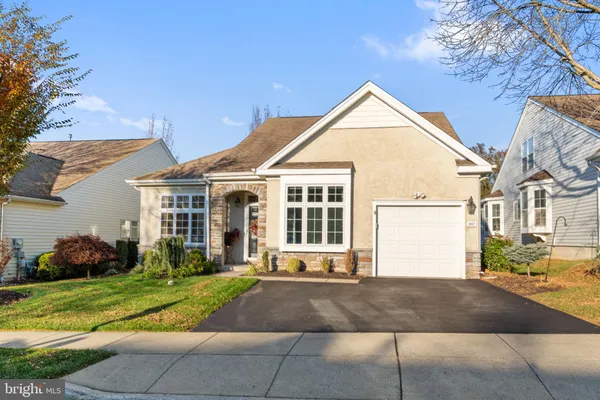 a view of a white house with a yard plants and large tree