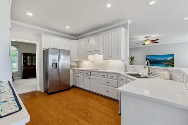 a kitchen with stainless steel appliances granite countertop a refrigerator sink and white cabinets