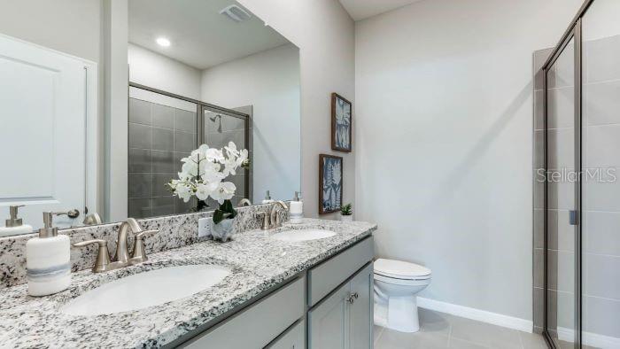 18024 Cropside Trail Lakewood Ranch, FL 34211 - Photo 13 of 42 a bathroom with a granite countertop sink a toilet and a mirror