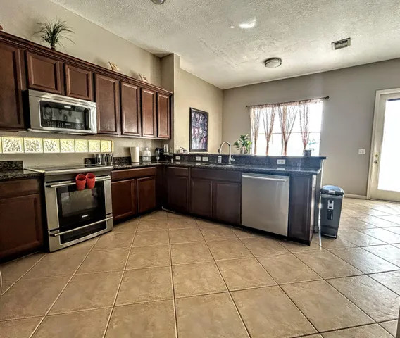 a large kitchen with stainless steel appliances granite countertop a stove granite counter tops and a window