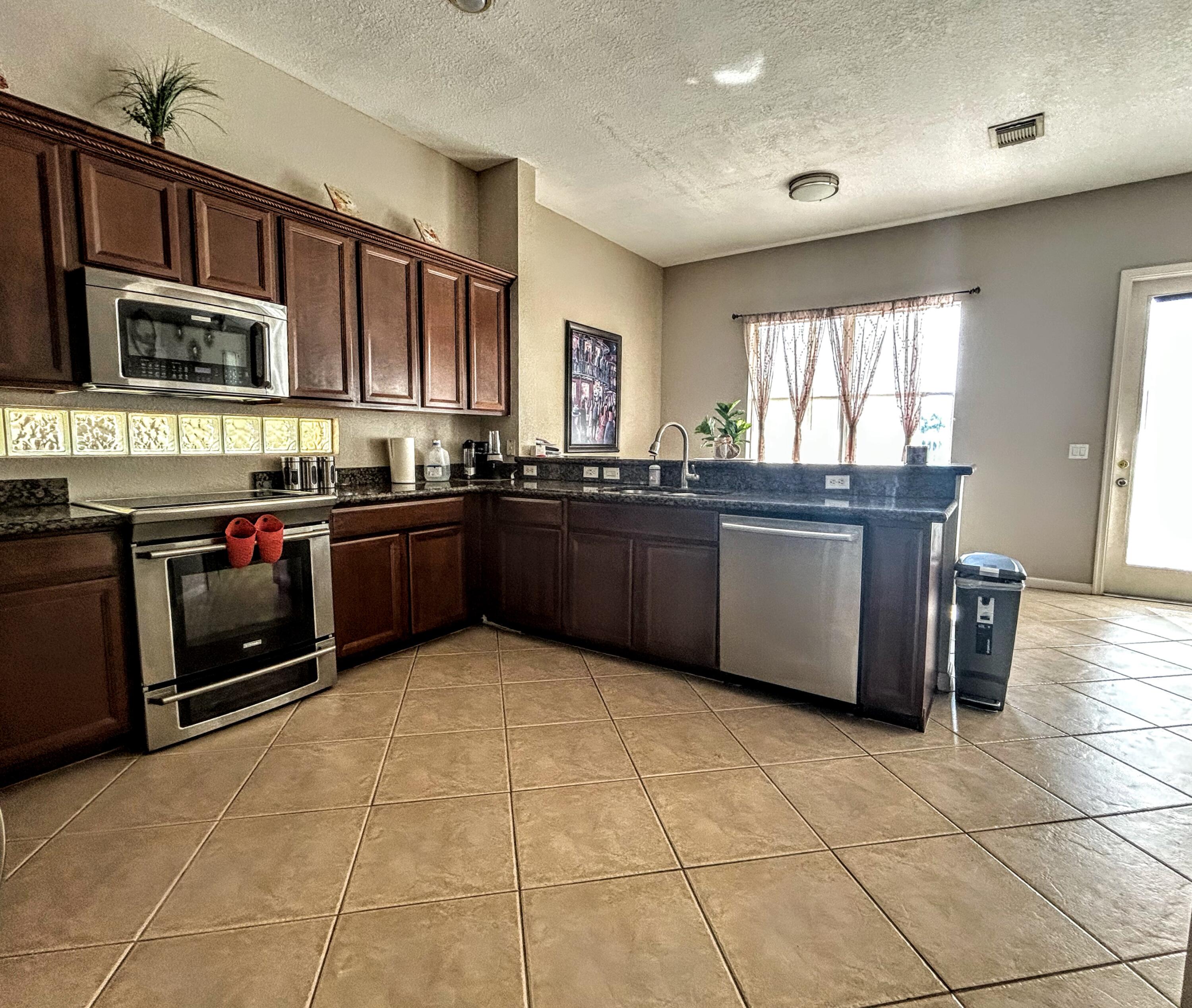 673 Gazetta Way West Palm Beach, FL 33413 - Photo 15 of 35 a large kitchen with stainless steel appliances granite countertop a stove granite counter tops and a window