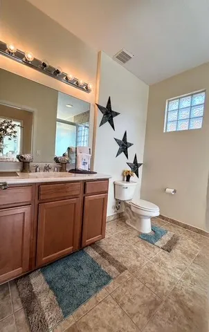 a bathroom with a granite countertop sink a toilet and a mirror