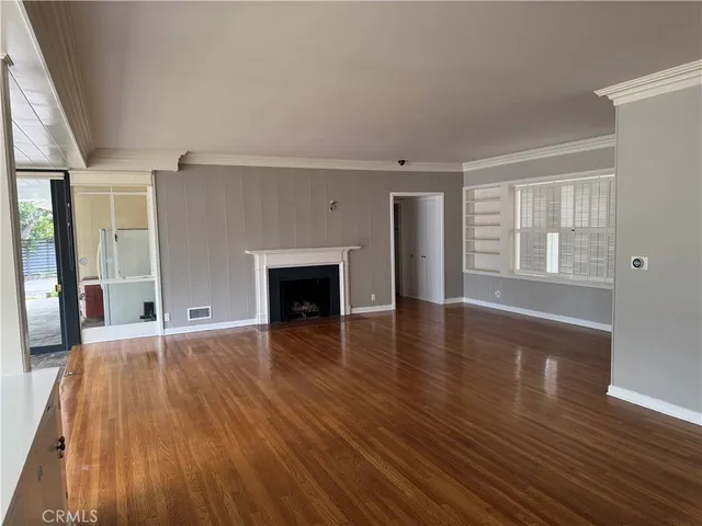 an empty room with wooden floor and fireplace