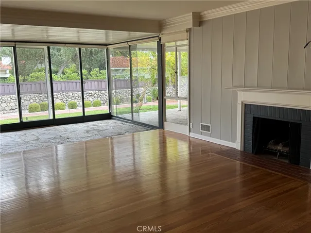a view of empty room with wooden floor and fireplace