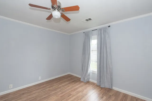 an empty room with wooden floor chandelier fan and windows