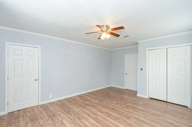 a view of a big room with wooden floor and a chandelier fan