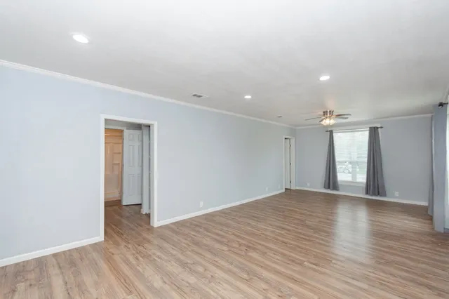 an empty room with wooden floor and windows