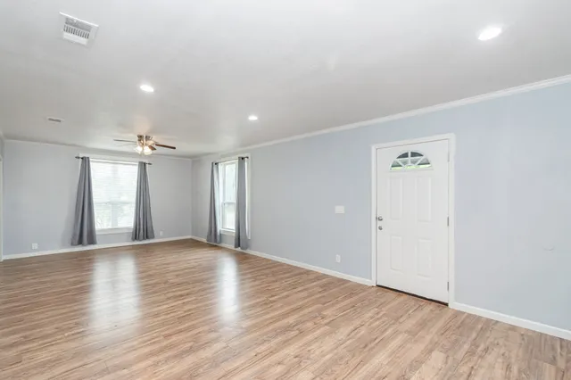 a view of an empty room with window and wooden floor