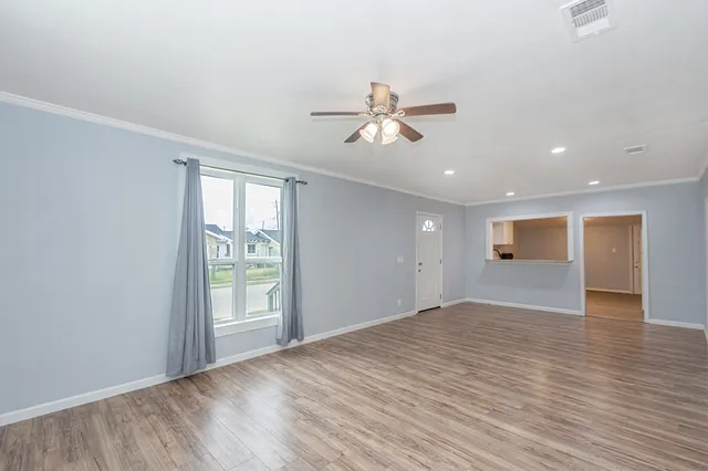 a view of empty room with wooden floor and fan