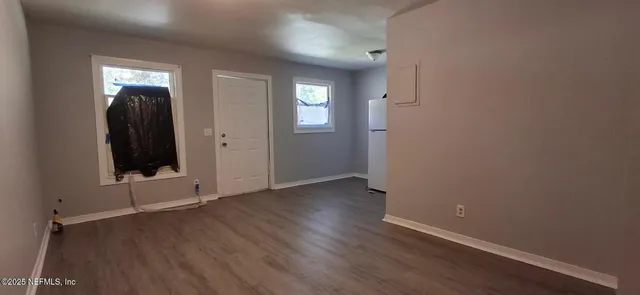 an empty room with wooden floor and windows