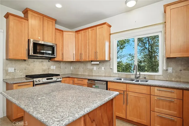 a kitchen with stainless steel appliances granite countertop wooden cabinets a sink and a window