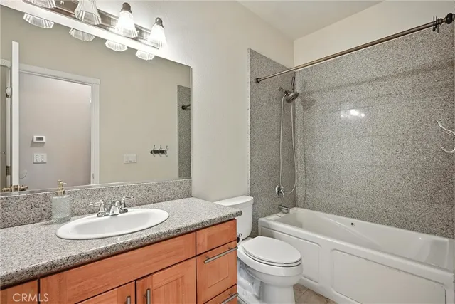 a bathroom with a granite countertop sink a toilet a mirror and shower