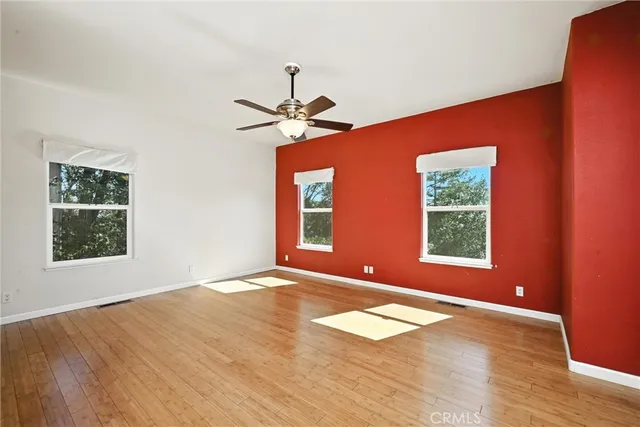 a view of an empty room with window and wooden floor