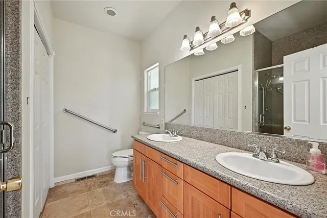 a bathroom with a granite countertop double vanity sink mirror and toilet