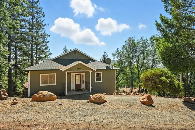 a front view of a house with garden and trees