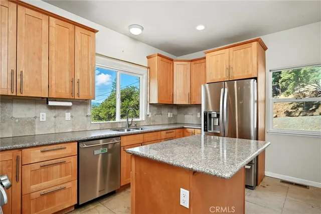 a kitchen with stainless steel appliances granite countertop a sink a refrigerator and a granite counter tops