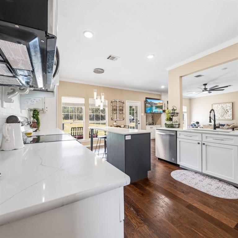 785 Tweedy Road Valley Mills, TX 76689 - Photo 10 of 40 Modern kitchen featuring white cabinetry, light countertops, an eat-at island with a dark base, stainless steel appliances, and wood-finish flooring