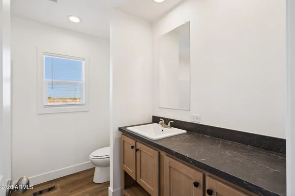 a bathroom with a granite countertop sink a toilet and a mirror