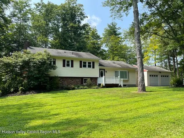 a front view of a house with a garden and trees