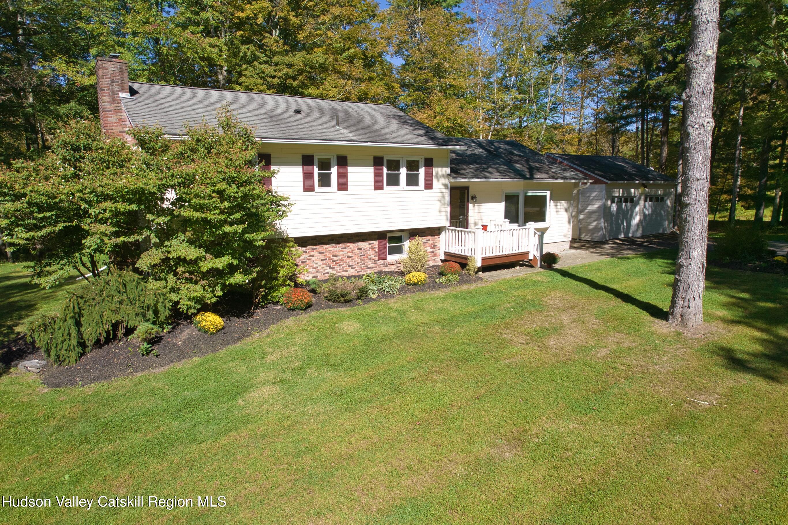 177 Buck Road Stone Ridge, NY 12484 - Photo 3 of 37 a front view of a house with a garden and trees