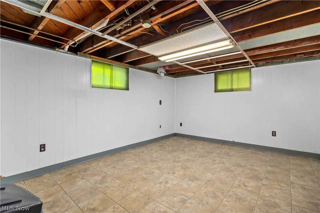 9988 West Ridge Road Elyria, OH 44035 - Photo 37 of 49 Room featuring paneled walls, exposed ceiling joists, and a tiled floor