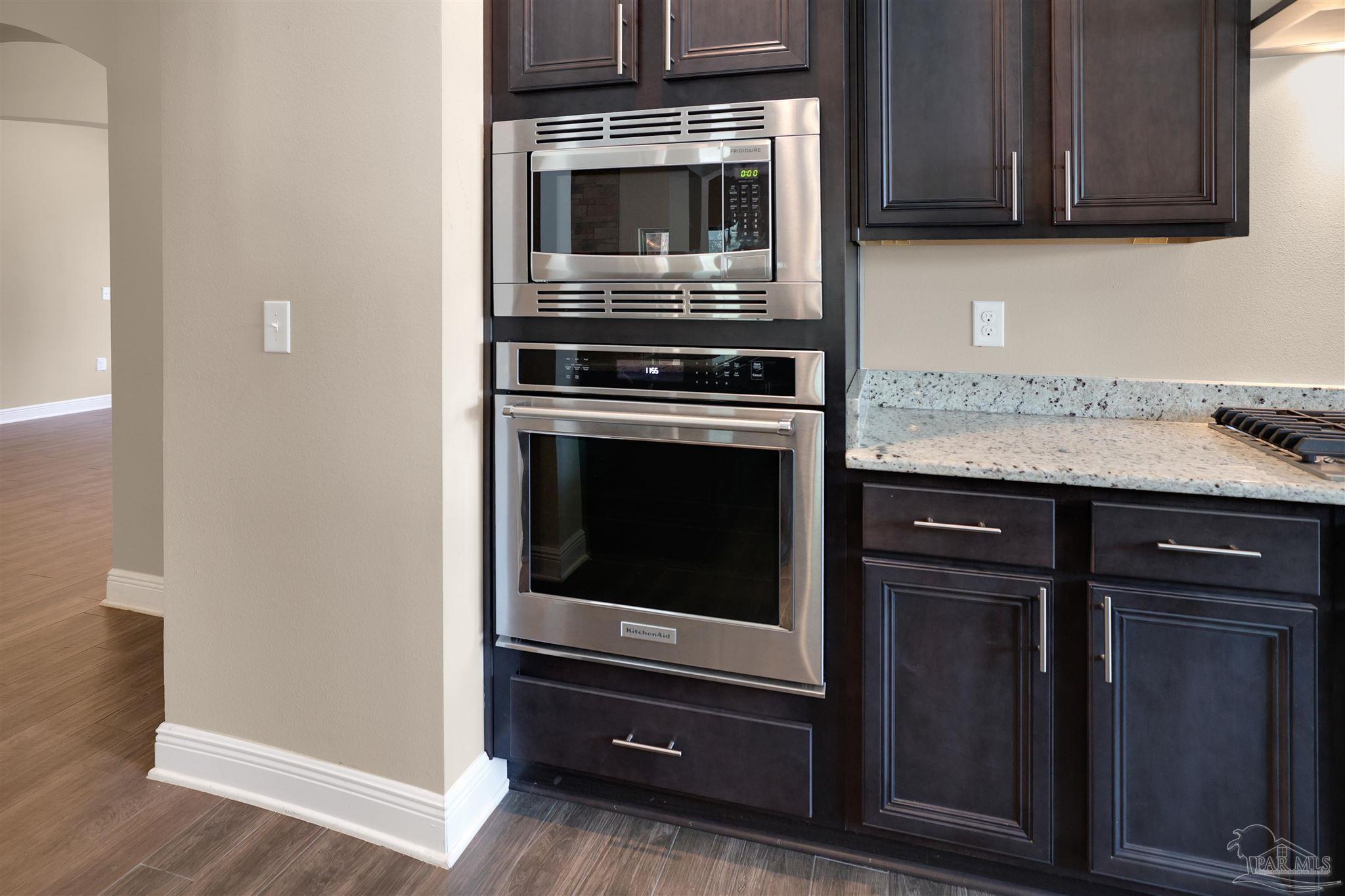5847 Mossy Creek Lane Pace, FL 32571 - Photo 12 of 50 a kitchen with granite countertop stainless steel appliances and wooden cabinets