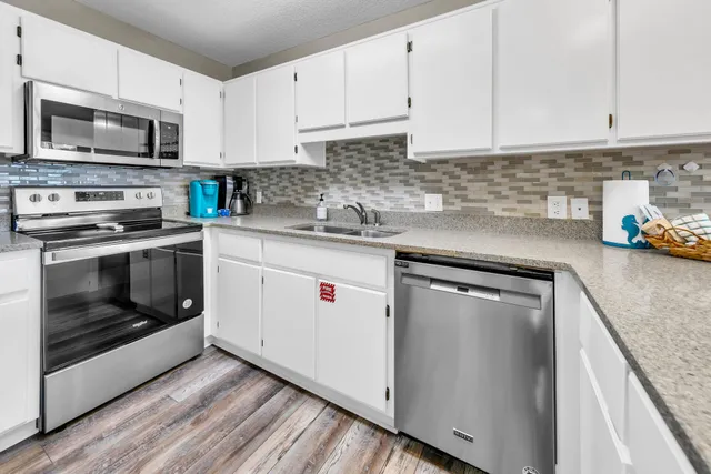 a kitchen with stainless steel appliances granite countertop a stove a sink and a microwave