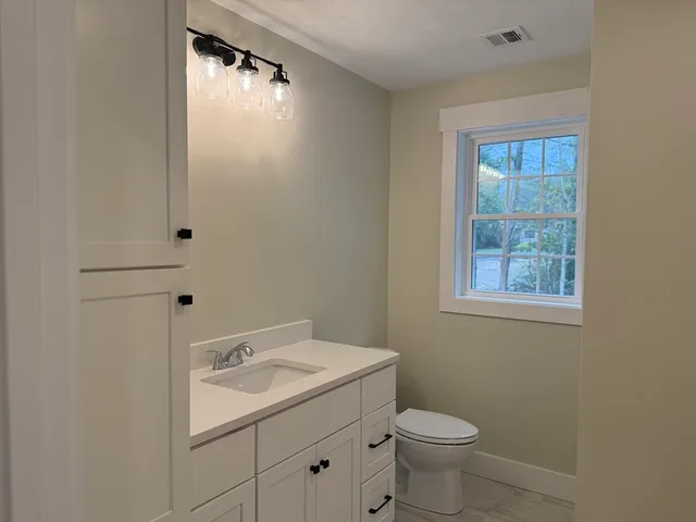 a bathroom with a sink toilet and window
