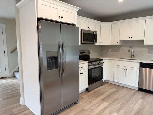 a kitchen with stainless steel appliances a refrigerator stove and white cabinets