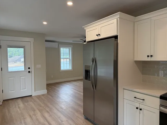 a view of a kitchen with refrigerator and wooden floor