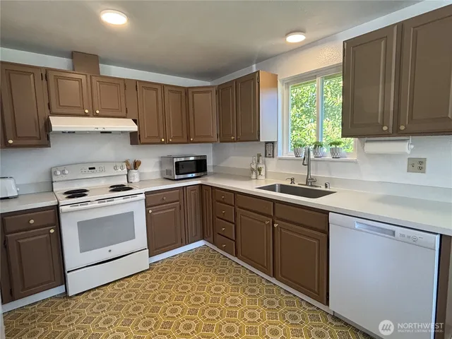 a kitchen with a sink cabinets appliances and a window