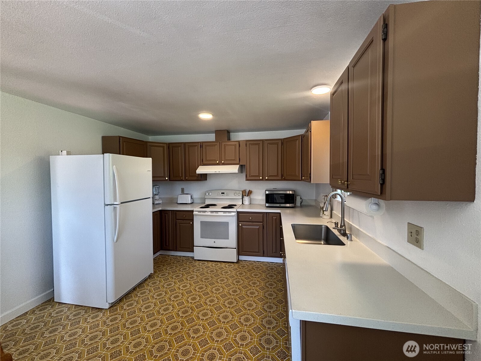 7265 East Harrison Street, Unit A Port Orchard, WA 98366 - Photo 6 of 17 a kitchen with a sink a refrigerator and a stove top oven with wooden floor