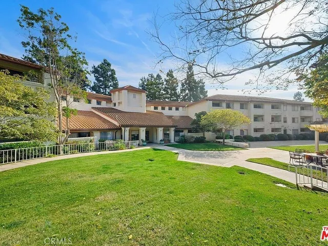 a view of a house with a big yard plants and large trees