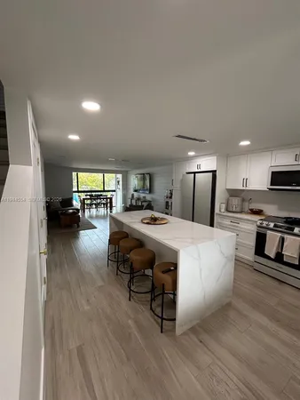 a living room with furniture and kitchen view with wooden floor