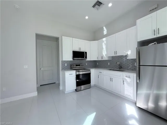 a kitchen with granite countertop white cabinets and stainless steel appliances