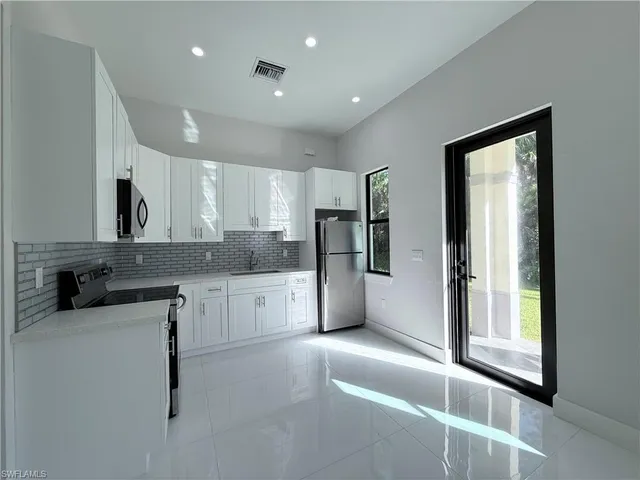 a kitchen with a refrigerator and white cabinets
