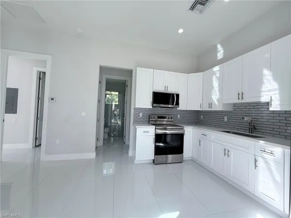 a kitchen with granite countertop white cabinets and stainless steel appliances