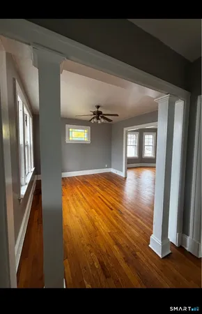 a view of empty room with wooden floor and fan