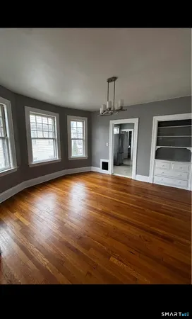 a view of an empty room with window and wooden floor