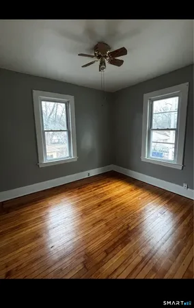 a view of empty room with wooden floor and fan