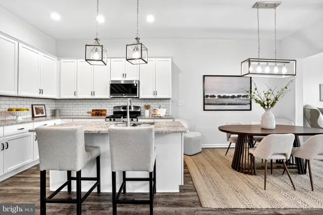 a living room with stainless steel appliances kitchen island granite countertop a stove a sink a dining table and chairs with wooden floor