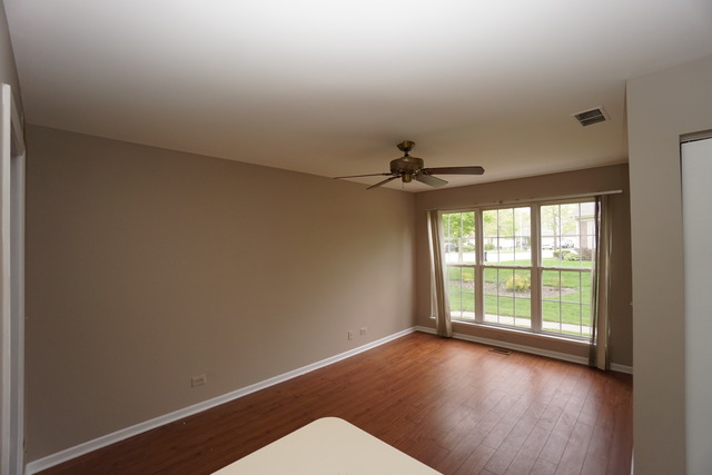 1129 Coldspring Road Elgin, IL 60120 - Photo 4 of 18 an empty room with wooden floor fan and windows