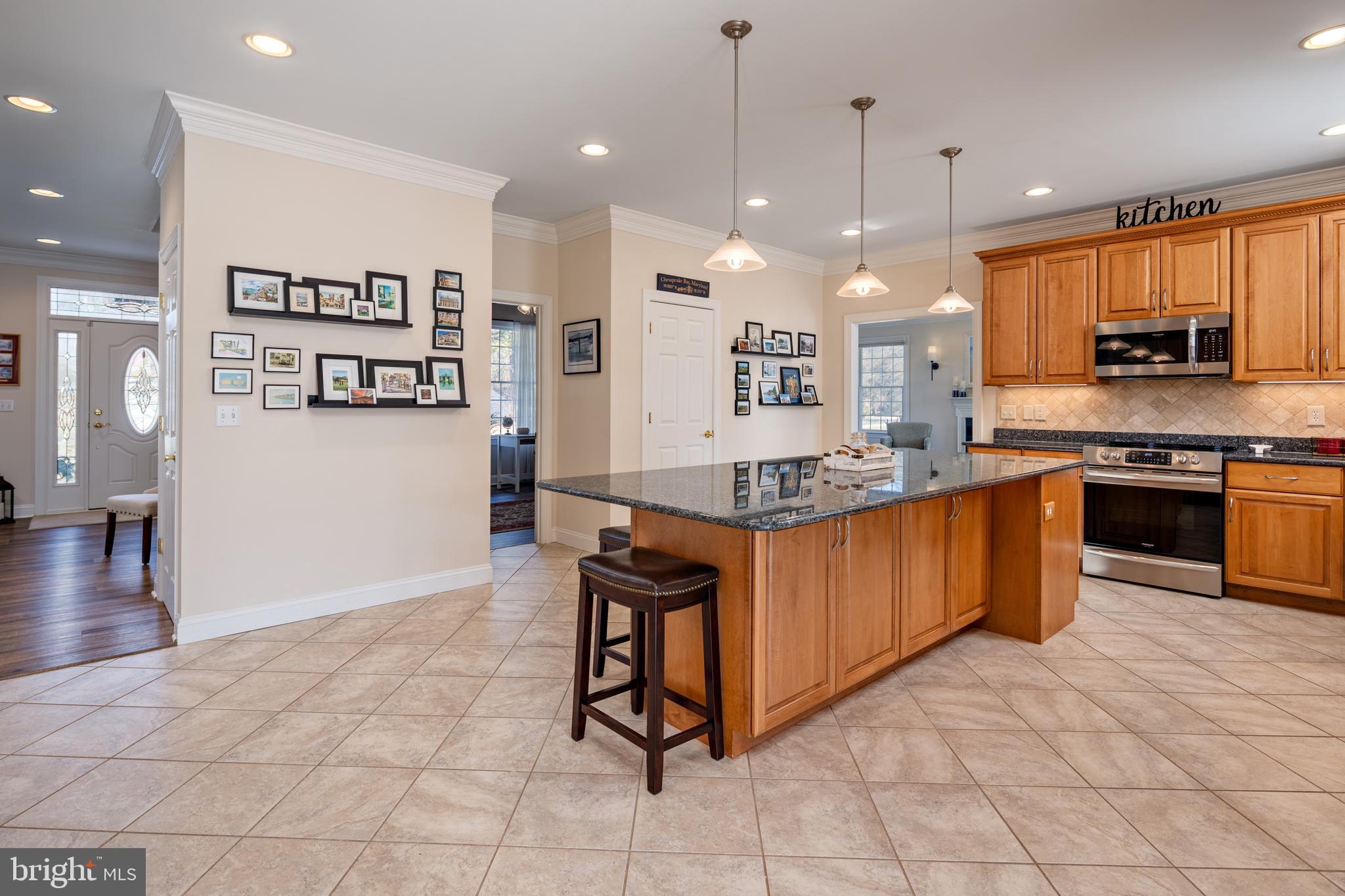 115 Cedar Road Chester, MD 21619 - Photo 12 of 71 a large kitchen with kitchen island granite countertop a stove a sink a dining table and chairs