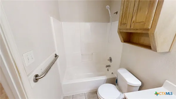a bathroom with a granite countertop toilet and a tub