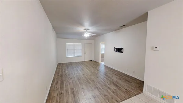 an empty room with wooden floor and windows