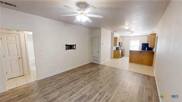 a view of a electric appliances in kitchen and empty room with wooden floor