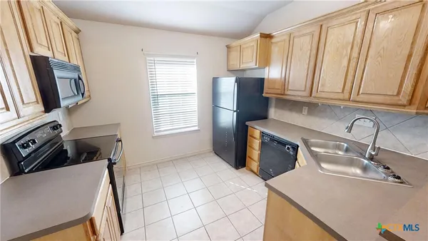a kitchen with stainless steel appliances a sink a stove a refrigerator a sink a counter space and cabinets