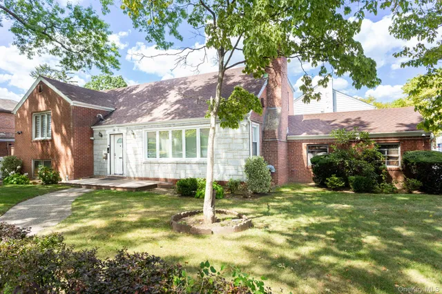 a view of a house with a big yard and large tree
