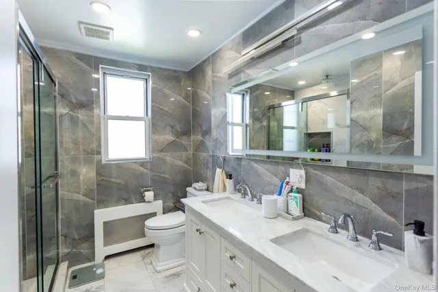 a bathroom with a double vanity sink toilet and shower