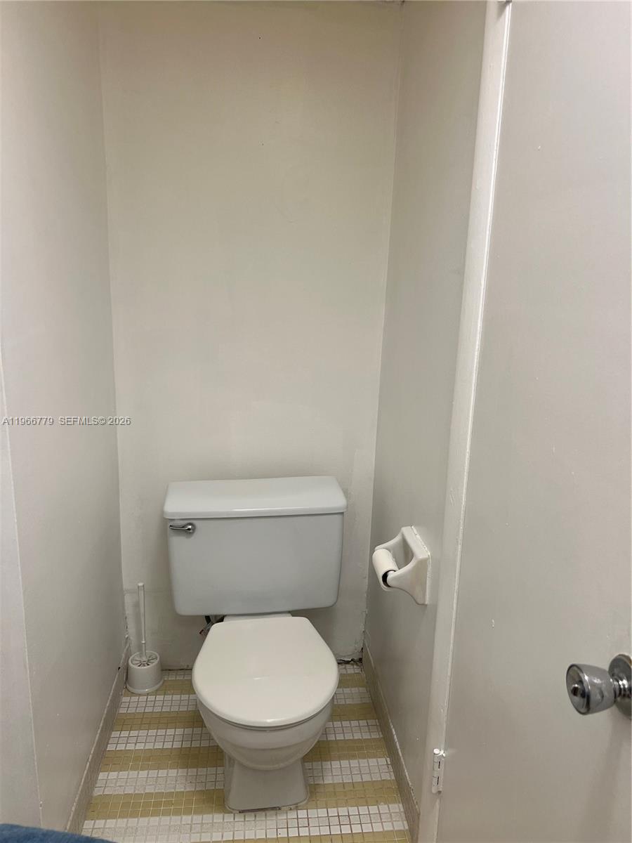 3690 Inverrary Drive, Unit 1K Lauderhill, FL 33319 - Photo 12 of 34 a toilet sitting in a bathroom next to a wooden wall